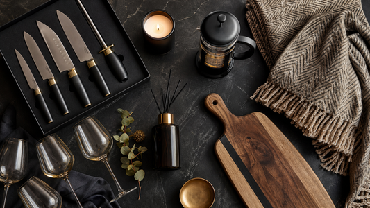 New home gifts UK 2026 — flat lay of practical and stylish housewarming gift ideas including chef knife set, candle, coffee maker and home accessories on dark slate